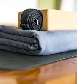 a yoga strap, bolster, and block rest on the floor.