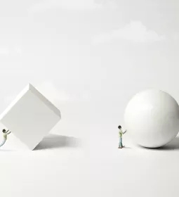 A figure trying to roll a white 3D block, and a second figure rolling a white sphere.