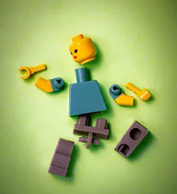 A LEGO figure of a person with all the parts unattached and scattered.