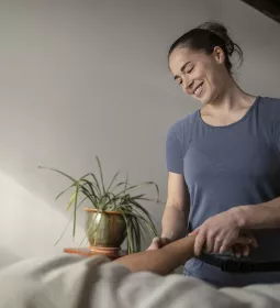 A massage therapist smiles while performing acupressure.