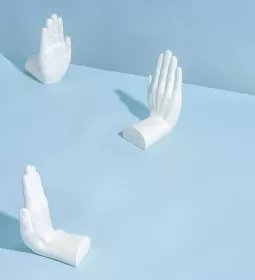 Three sculptures of hands putting their hands up.