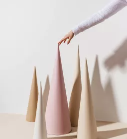 A person puts the tip of their finger on the pointy top of a cone with other cones around.