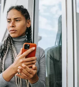A woman holding a smartphone, looking disappointed at a message.