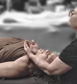 Woman gives massage to client lying supine on massage table.