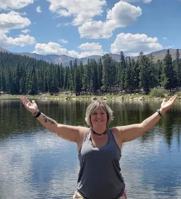 Heather Topoly standing with arms outstretched in the mountains.