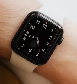a smartwatch on a person's wrist displaying an analog clockface.