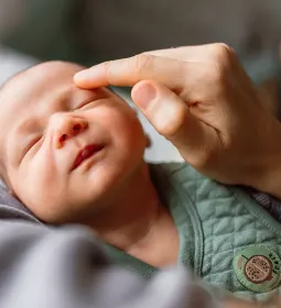 A practitioner delivers craniosacral therapy to a baby but touching the baby above its eyebrow.