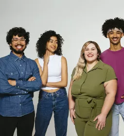 Four individuals of various ethnicities smile for a photo.