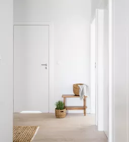A hallway in an office leading to a small table with a towel and a door.