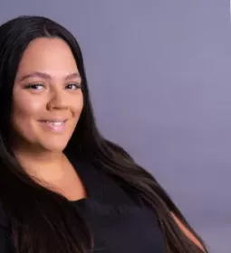 carol reyes ryan with long dark hair in a black shirt smiling.