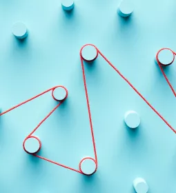 A red string winds around pegs on a blue board.