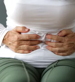A woman clutches her stomach.