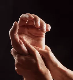 Two hands massage a third hand.