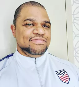 Desmond Diaz in a US Olympic team uniform smiles at the camera.