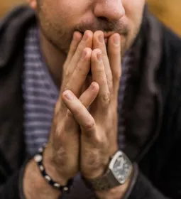 A man holds his hands together in front of his face.
