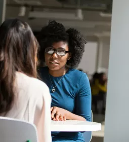 Two women at a table are seated talking.
