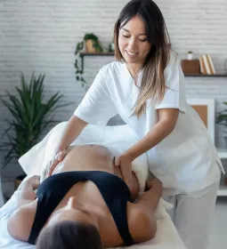 A massage therapist massages a pregnant woman on a table.