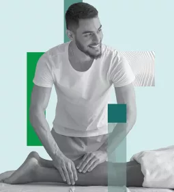 A massage therapist works on a prone client's lower leg.