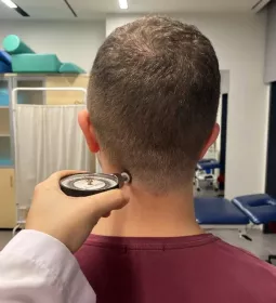 A client has a pain pressure threshold algometer held at their neck.