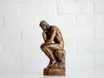 A miniature version of the statue "The Thinker" stands on a table.