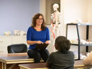 An instructor chats with people in an anatomy classroom.