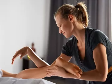 a female MT uses both her hands, arms, and elbows to massage a client.