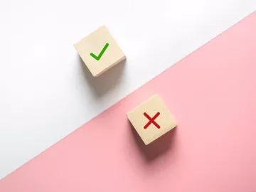 two wooden dice, one with a check mark and one with an X. 