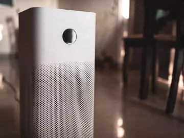 a white air purifier unit plugged into a wall.