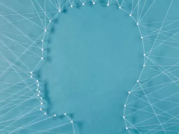 a web of string and needles connects to form the shape of a face. 