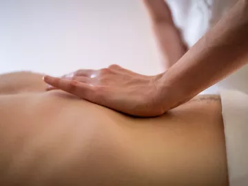 an MT's hand on the abdomen of a draped client.