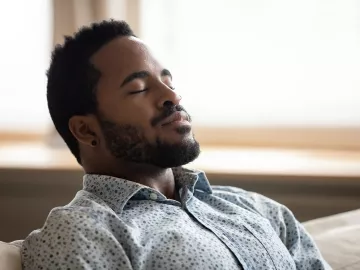 A Black man leans back and takes a deep breath.
