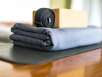 a yoga strap, bolster, and block rest on the floor.