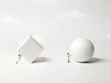 A figure trying to roll a white 3D block, and a second figure rolling a white sphere.