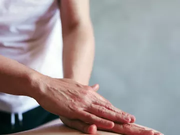 A practitioner lays hands on a client.