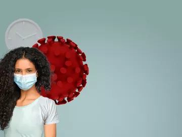 A woman with curly long hair wearing a face mask stands in front of a cartoon red cell.