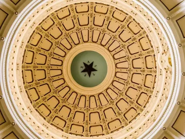 Gold dome of a ceiling inside a government building.