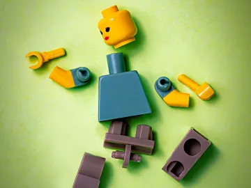 A LEGO figure of a person with all the parts unattached and scattered.