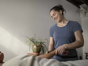 A massage therapist smiles while performing acupressure.