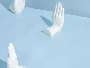 Three sculptures of hands putting their hands up.
