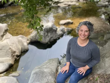  A professional portrait of Kerry Jordan sitting by a creek.