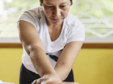 Woman massages the leg of a client. 