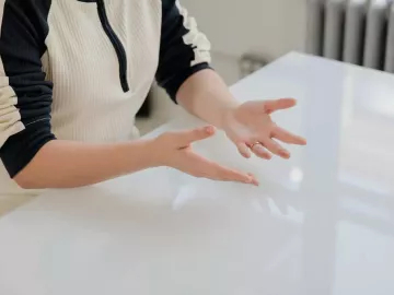 A person seated at a table, palms facing up.