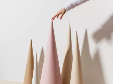 A person puts the tip of their finger on the pointy top of a cone with other cones around.