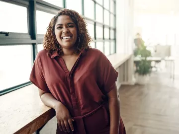 A smiling woman leaning on a countertop.