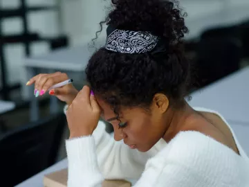 An African American woman in a white blouse taking a written test.