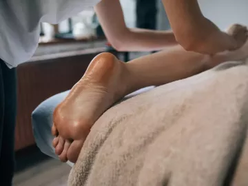 A massage therapist works on the legs of a client who is face down on a table.