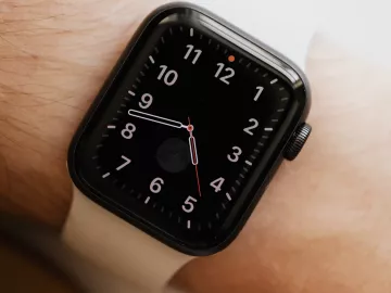 a smartwatch on a person's wrist displaying an analog clockface.