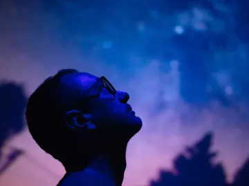 A man gaves up into the starry night sky with his head tilted backward.