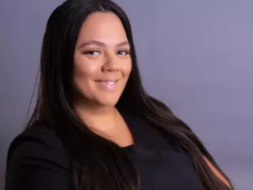 carol reyes ryan with long dark hair in a black shirt smiling. 