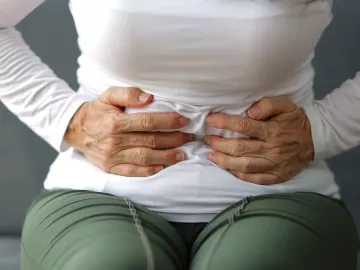 A woman clutches her stomach.